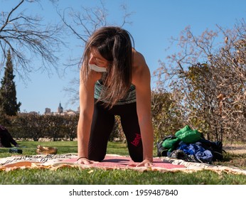 A Brunette Woman Doing Yoga Class In A Park On A Sunny Day And Wearing A Face Mask