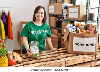 Brunette woman with down syndrome by box checking donated toys and charity jar at donations stand - Shutterstock ID 2208837067