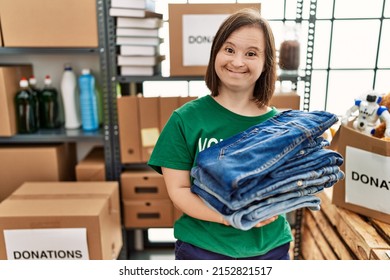 Brunette woman with down syndrome holding folded jeans at donations stand