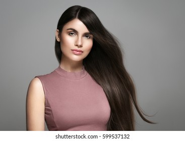 Brunette Woman girl with long and shiny wavy smooth hair and red lips. Beautiful model with smooth hairstyle over gray background. - Shutterstock ID 599537132