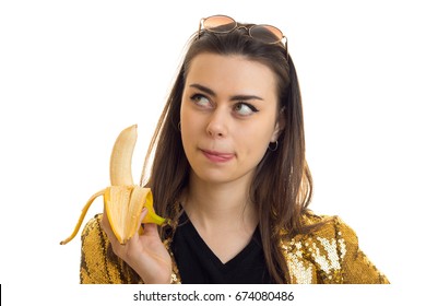 Brunette Woman In Golden Jacket Eating A Banana