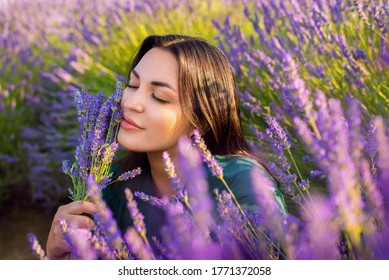 Brunette woman in green dress is posing at lavender field. Lavender Fields Provence Woman sensual portraits close up at summer sunny day. 