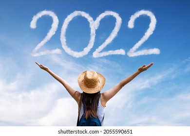 Brunette woman greets the 2022 against clouds - Shutterstock ID 2055590651