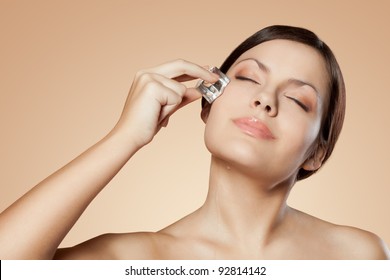 Brunette Woman Holding Ice Cube On Her Face