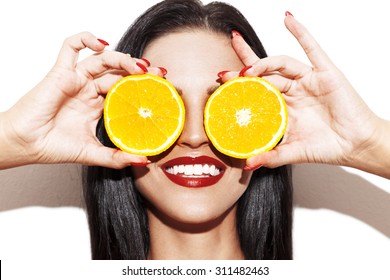Brunette woman holding orange rings at eyes