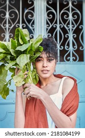 Brunette Woman Holding Salad Leafs Near Her Face And Looking At The Camera