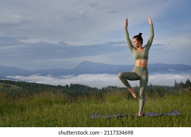 Brunette woman keeping balance and preparing for practice Sun Salutation. Healthy athletic female standing on one leg on yoga mat, deeply breathing in mountain. Concept of recreation.