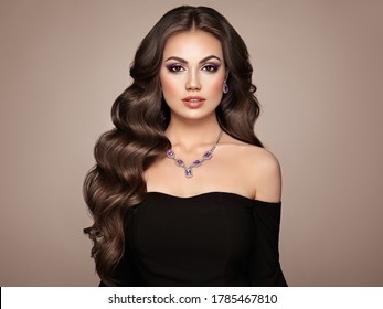 Brunette Woman With Long And Volume Shiny Wavy Hair . Beautiful Model With Curly Hairstyle. Perfect Make-up. Beauty Style Model