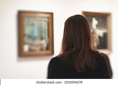 Brunette Woman Looking At Artwork In Museum. Rear View.