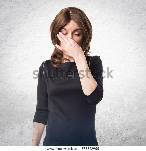 Brunette woman making smelling bad gesture\
over textured\
background