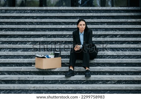 A brunette woman sits on the steps outside, feeling the effects of her job loss and the struggle to find work in a difficult job market. Female Looking Disappointed After Being Laid Off