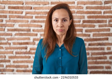 Brunette woman standing over bricks wall skeptic and nervous, frowning upset because of problem. negative person.  - Shutterstock ID 2196310533