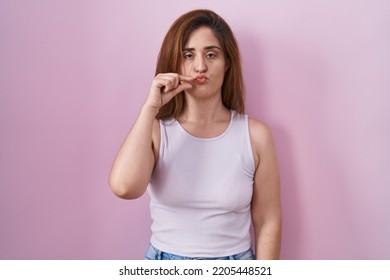 Brunette Woman Standing Over Pink Background Mouth And Lips Shut As Zip With Fingers. Secret And Silent, Taboo Talking 