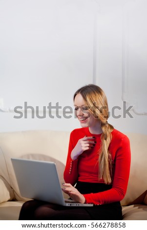 Brunette woman talking in a video call on line with headphones and a laptop on the couch at home