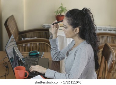 Brunette Woman Telecommuting At Home, Pensive Looking At Her Computer Screen