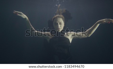 Brunette woman underwater swimming pool on dark background