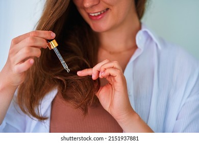 Brunette Woman Using Dropper For Pampering And Moisturizing Hair Ends With Vitamin Essential Oil Serum