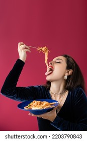 Brunette Woman In Velour Dress Eating Delicious Spaghetti From Blue Plate Isolated On Red