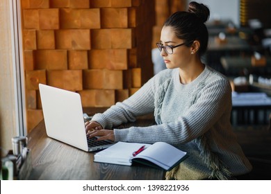 brunette woman working on her laptop at a restaurant - Shutterstock ID 1398221936