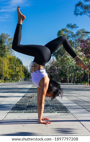 brunette and young fitness woman practicing handstand yoga wearing sportswear. wellness, exercise, healthy lifestyle