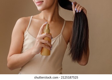 Brunette Young Woman Applying Hair Spray On Her Ponytail