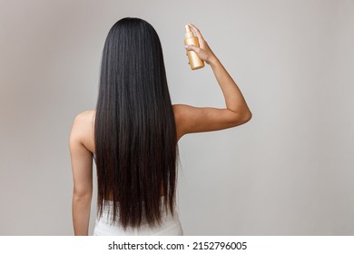 Brunette young woman applying hair spray on hair - Shutterstock ID 2152796005
