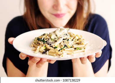 brunette young woman holding a white plate with pasta and cheese