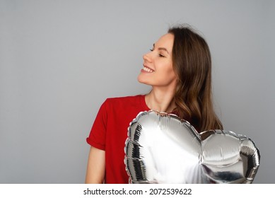 Brunette Young Woman In Redt-shirt With Silver Air Heart Ballon, Party And Celebrate Theme, Studio Portrait On Grey Background