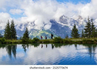 Brunni, Switzerland - August 06. 2021: People Hiking Along A Mountain Lake Haerzlisee Above The Engelberg In Titlis. The Region Is A Popular Recreation Place, Which Offers Diverse Outdoor Activ