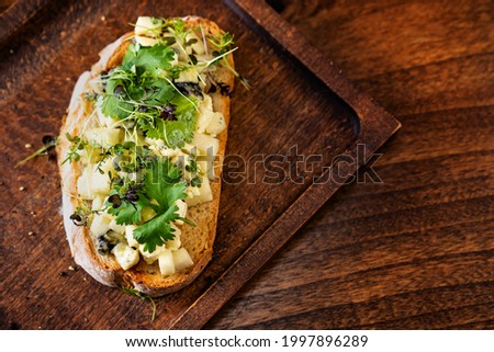 bruschetta with cheese and greens on a wooden cutting board for photos and video shooting. work as a food stylist and photographer. restaurant menu and kafe