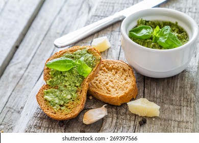 Bruschetta with fresh pesto sauce and basil leafs on rustic wood background