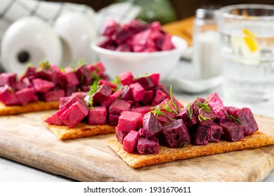 Bruschetta with pickled beetroot, apple and mayonnaise. Sandwich or crostini on a serving wooden board on a light gray table. Bread with traditional Scandinavian beet  salad