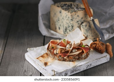 
Bruschetta with prosciutto, dried figs and gorgonzola cheese on wooden background - Powered by Shutterstock