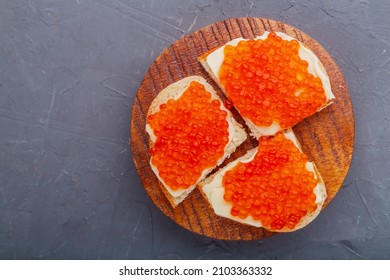 Bruschetta with red caviar on a wooden board on a gray background. Copy place Horizontal photo