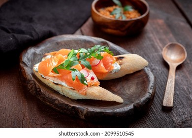Bruschetta with salmon, cottage cheese and arugula on a white baguette. Breakfast appetizer, salmon sandwich