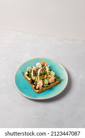 Bruschetta with salmon, cream cheese and vegetables on blue ceramic plate. Toast with salmon contemporary style. Salmon bruschetta in modern ceramic dishware. Handmade dinner plate