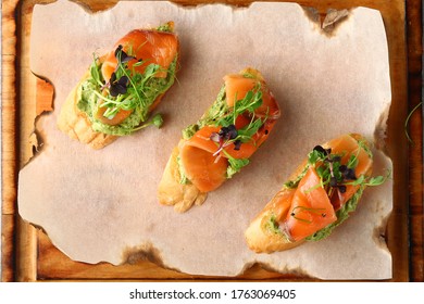 bruschetta with salmon on wood top view. Smoked salmon toast with guacamole and microgreen