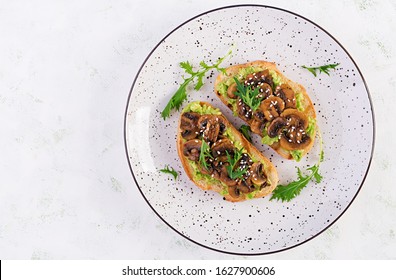 Bruschetta. Sandwich With Avocado, Fried Mushrooms, Sesame On A White Table. Vegetarian Food. Vegan Menu. Top View, Overhead