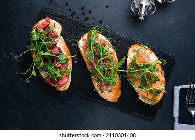 bruschetta set with parma, salmon and tuna, assorted set of bruschetta with salmon with herbs and tuna on black menu background