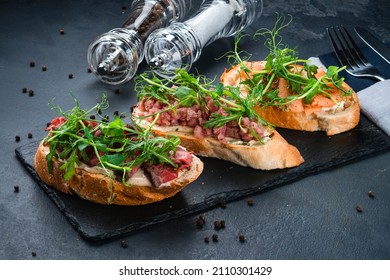 bruschetta set with parma, salmon and tuna, assorted set of bruschetta with salmon with herbs and tuna on black menu background