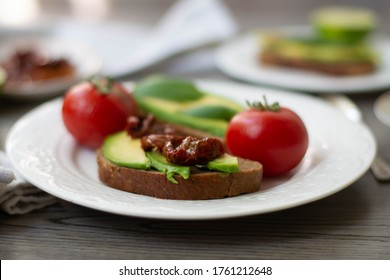 Bruschetta style rye bread toasts with avocado, sun-dried tomatoes, basil, dill and lime. Rustic dark wooden background - Powered by Shutterstock