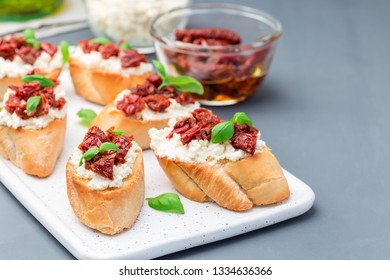 Bruschetta with sun dried tomato, feta and philadelphia cheese and basil on ceramic plate, horizontal, copy space