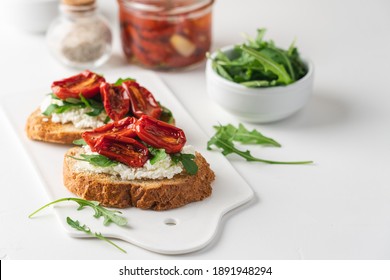 Bruschetta With Sun Dried Tomatoes And Arugula. Delicious Breakfast Or Wine Snack. White Background, Close-up, Top View