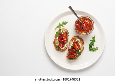 Bruschetta With Sun Dried Tomatoes And Arugula. Delicious Breakfast Or Wine Snack. White Background, Close-up, Top View