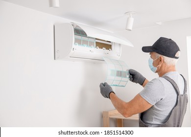 Brush Cleaning Air Conditioner From Dust. Worker In Gloves And Medical Mask Checks Filter.