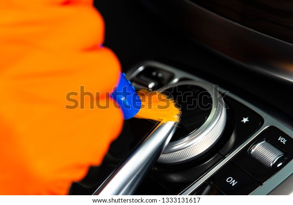 Brush cleaning off dust from the car interior\
details, control panel of the dashboard. A man cleaning car with\
cloth and brush. Car detailing.  Worker cleaning. Brush and\
cleaning solution to\
clean