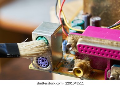 Brush Cleaning The Old Motherboard From Dust And Dirt.