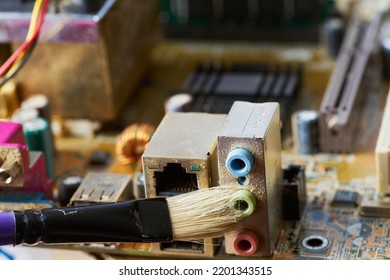 Brush Cleaning The Old Motherboard From Dust And Dirt.