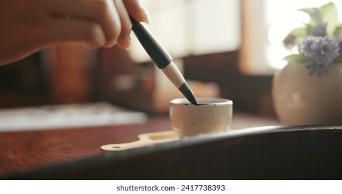 Brush, closeup and hands at a table for calligraphy, writing or ancient Japanese art in a house. Letter, communication and zoom on person fingers with traditional ink stroke, penmanship or art tool