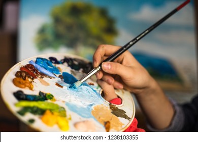 Brush in hand. Oil painting. Beatiful picture. Palette paint.